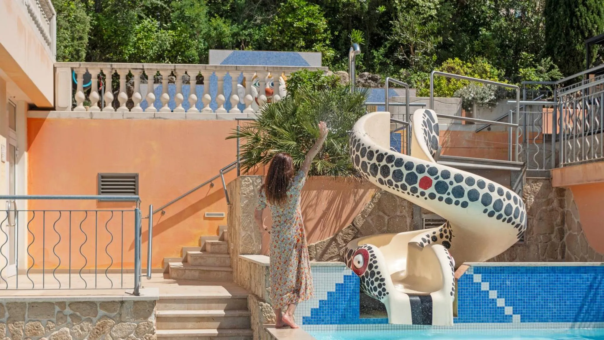 Une femme se tient près d'un toboggan aquatique au bord d'une piscine.