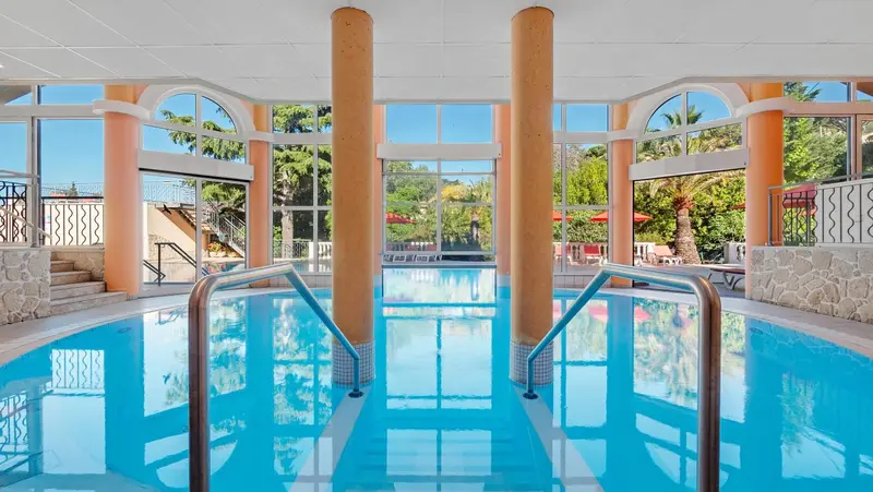 Une piscine intérieure lumineuse avec des colonnes et un accès par des marches.