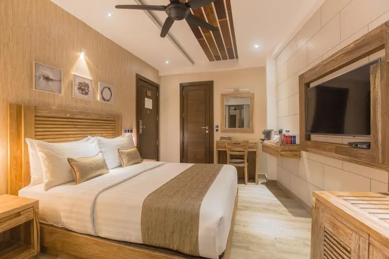 Une chambre lumineuse avec un grand lit et un bureau en bois.