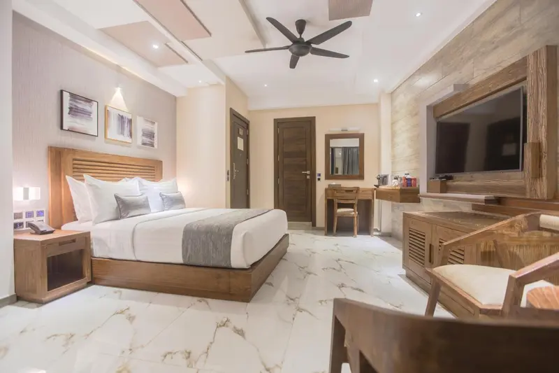 Une chambre lumineuse avec un grand lit et un téléviseur mural.