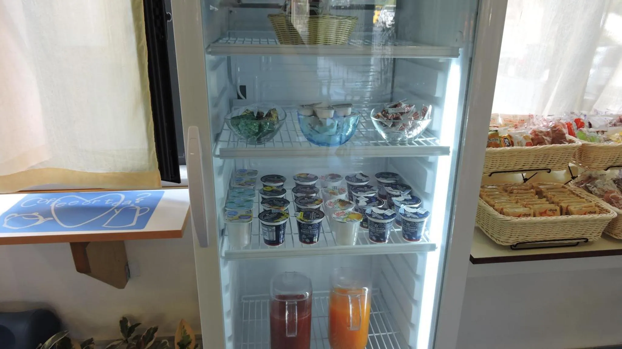 Un réfrigérateur rempli de yaourts, de fruits et de jus.