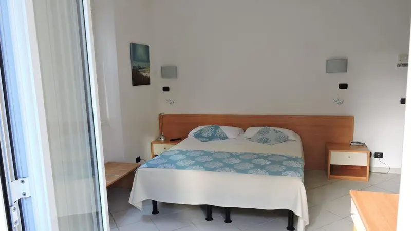 Une chambre lumineuse avec un grand lit recouvert d'une courtepointe bleue.