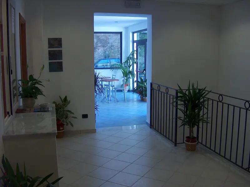 Un couloir lumineux mène à une salle de restauration avec des tables et des chaises.
