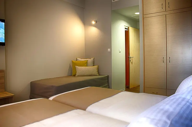 Une chambre avec deux lits simples et une armoire.