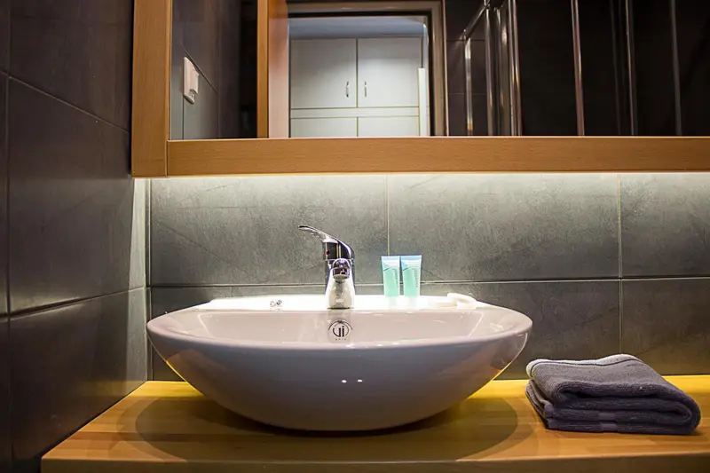Un lavabo blanc moderne avec un robinet chromé et des articles de toilette.