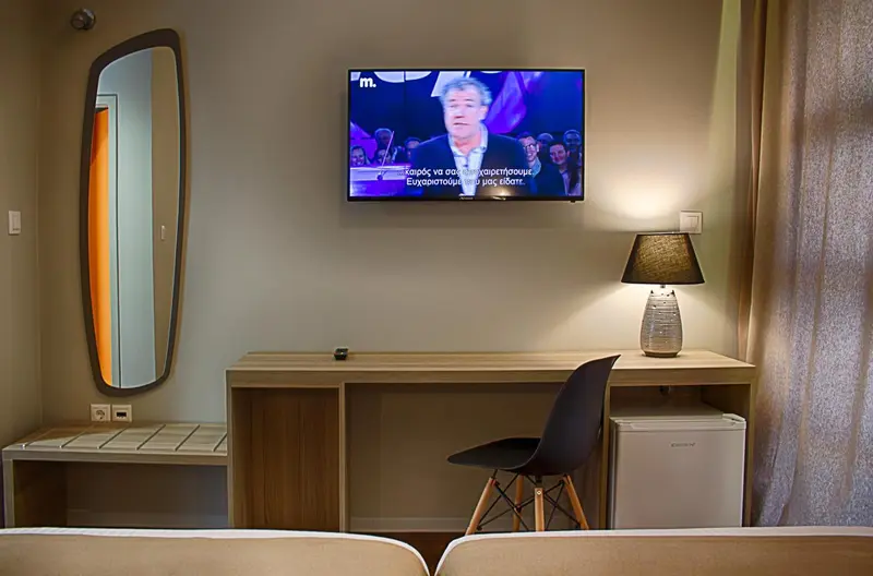 Une chambre d'hôtel moderne avec un bureau, un miroir et une télévision.