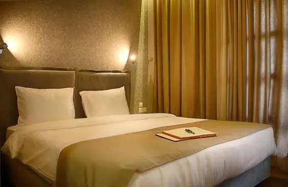 Un lit double avec oreillers blancs dans une chambre décorée de rideaux dorés.