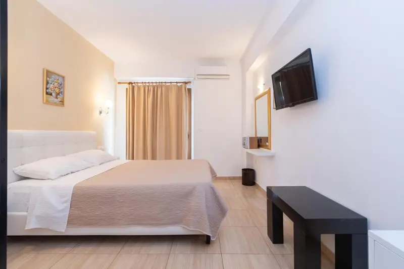 Une chambre lumineuse avec un grand lit et une télévision murale.