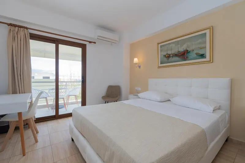Une chambre lumineuse avec un lit blanc et un accès à une terrasse.