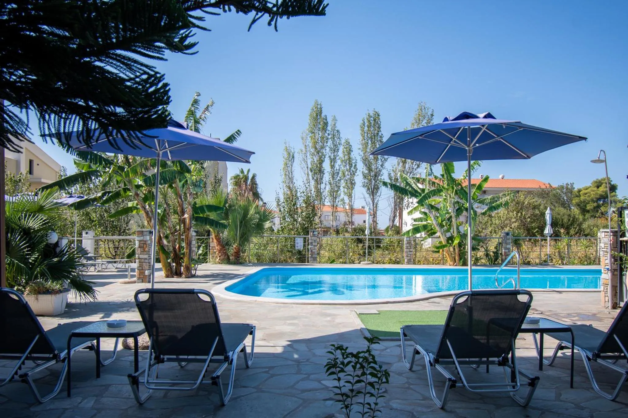 Transats bleus et parasols au bord d'une piscine ensoleillée.