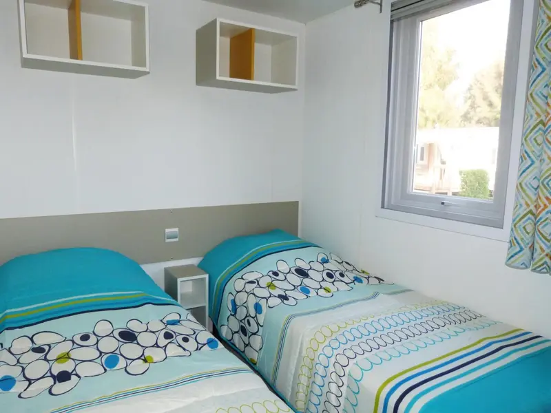 Une chambre lumineuse avec deux lits simples et une fenêtre.
