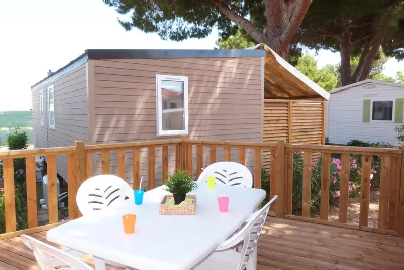 Terrasse en bois avec table et chaises devant un logement.