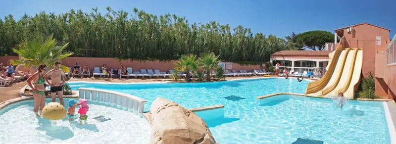 Une piscine avec toboggans et des personnes se baignant.