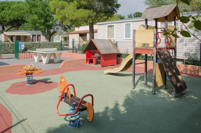 Aire de jeux colorée avec toboggan et balançoire sur sol amortissant.