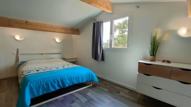 Une chambre lumineuse avec un lit fait et une commode.
