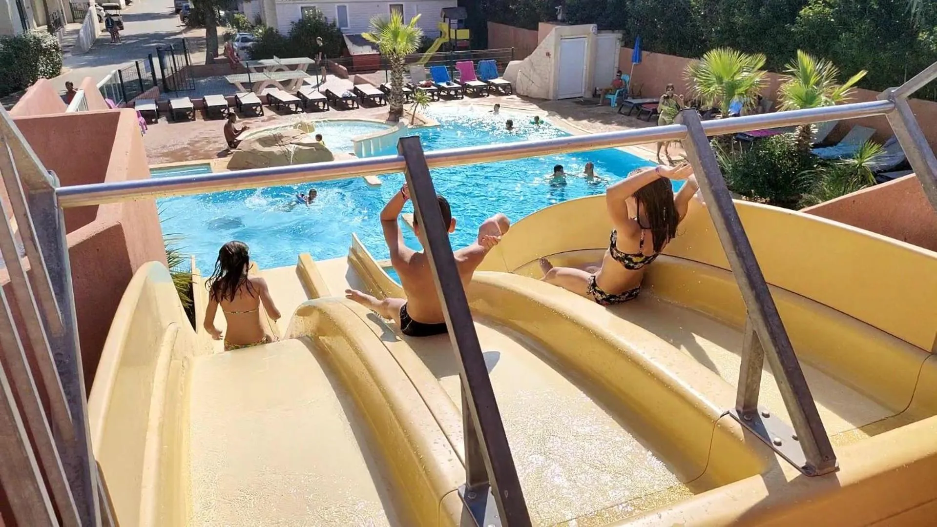 Des personnes se détendent au bord d'une piscine avec toboggans.