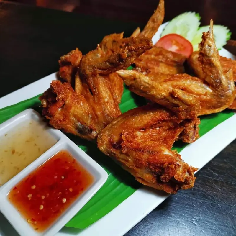 Assiette de poulet frit pané accompagnée de sauces et de légumes.