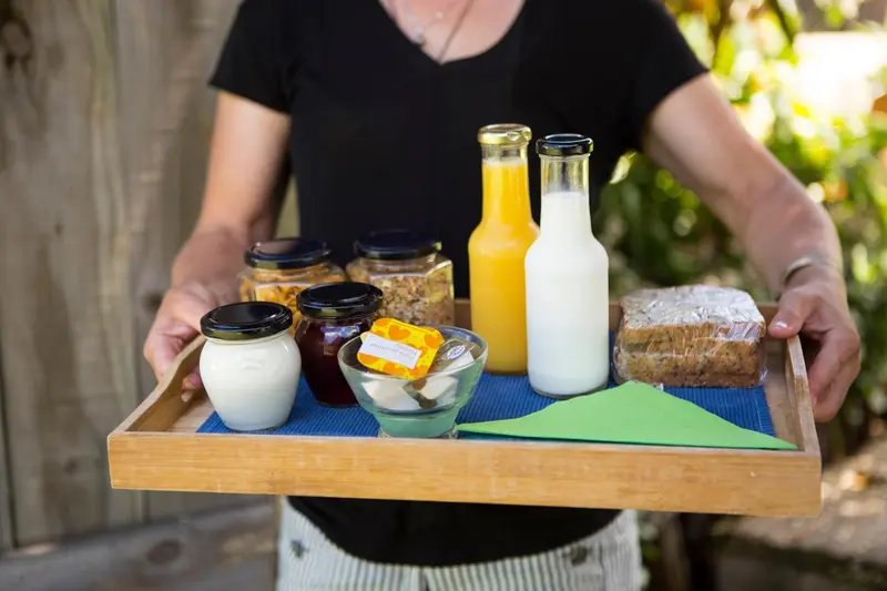Une personne porte un plateau garni de boissons et de nourriture.
