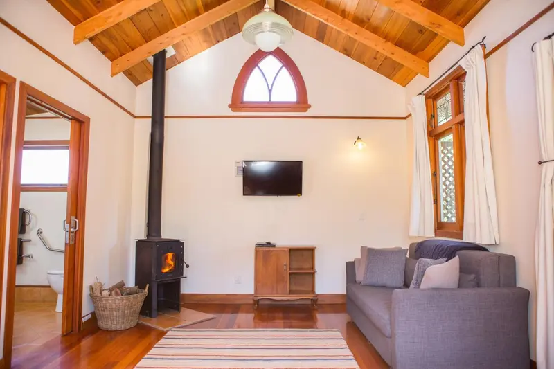 Interieur chaleureux avec canape, televiseur et poele a bois.