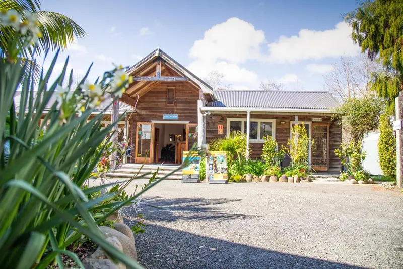 Bâtiment en bois avec une entrée ombragée et un jardin fleuri.