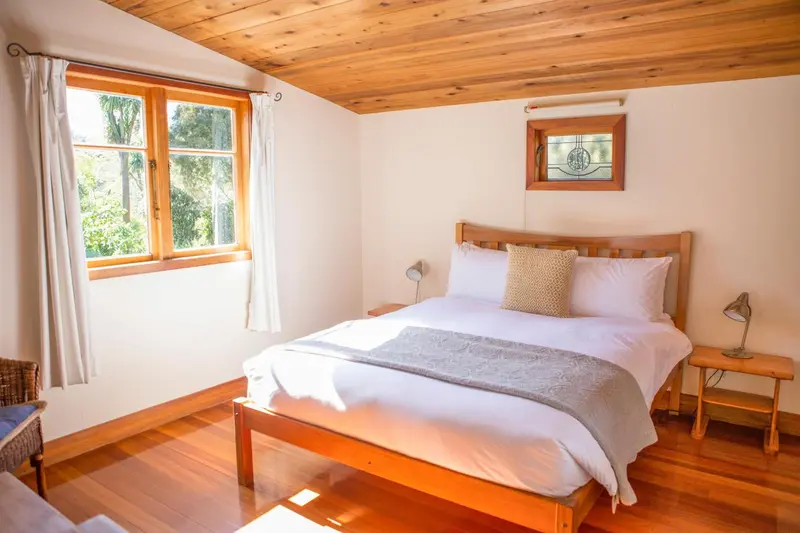 Une chambre lumineuse avec un lit double et une fenêtre donnant sur la végétation.