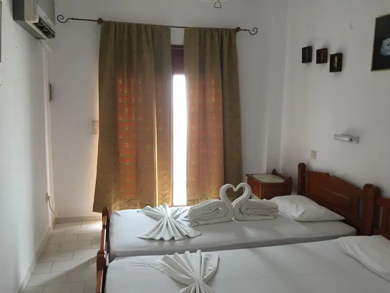 Une chambre lumineuse avec deux lits simples décorés de serviettes en forme de cygnes.