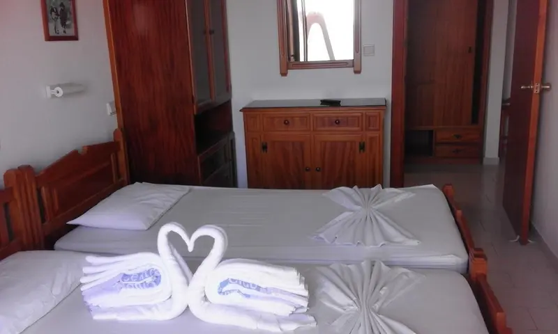 Une chambre lumineuse avec un lit décoré de serviettes en forme de cygnes.