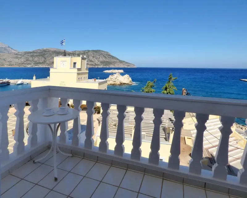 Terrasse carree avec garde-corps blanc et mobilier de jardin donnant sur la mer.