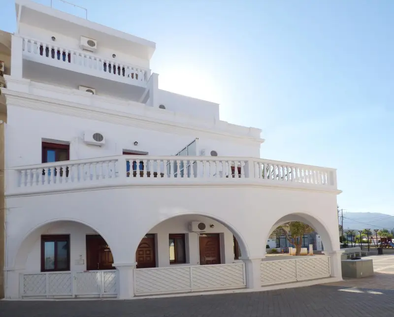Façade blanche d'un bâtiment avec des arches et des balcons.