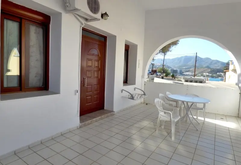 Une terrasse carree pavee de carrelage blanc, avec une table et des chaises en plastique.