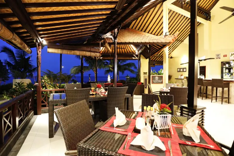 Terrasse aménagée avec tables et chaises, vue sur la mer au crépuscule.