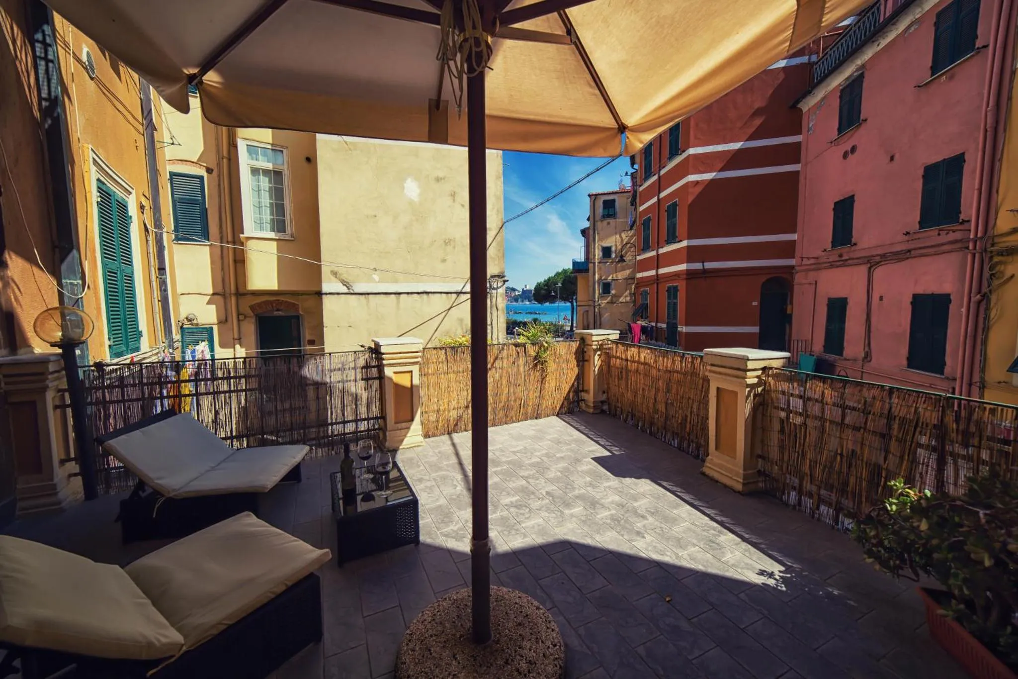 Terrasse ombragée avec mobilier de détente et vue sur des bâtiments colorés.