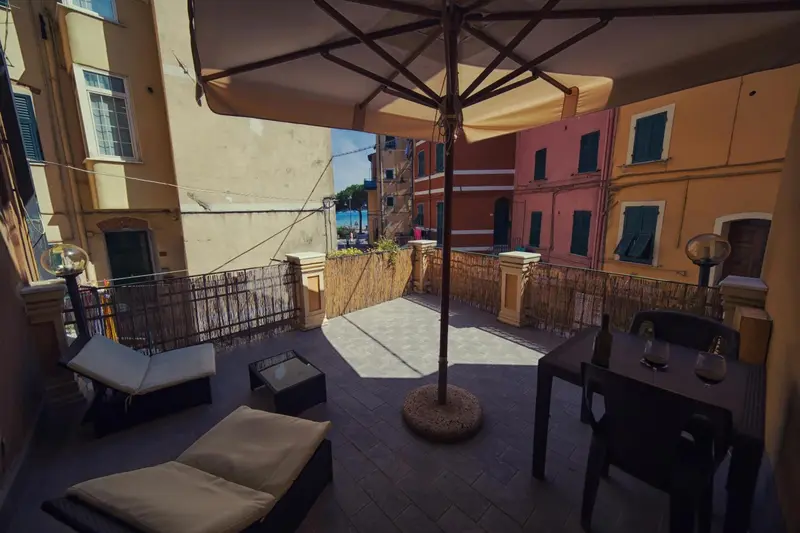 Terrasse ombragée avec mobilier de jardin et vue sur des bâtiments colorés.