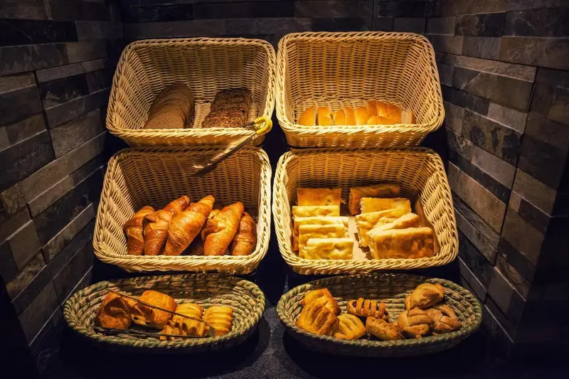 Des paniers de viennoiseries et de pains sont présentés sur un comptoir.