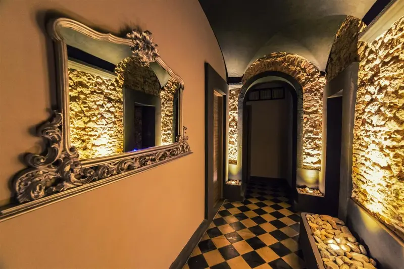 Couloir intérieur avec murs en pierre et miroirs décoratifs.