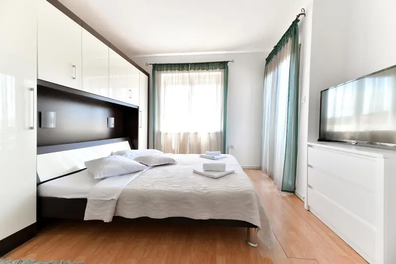 Une chambre lumineuse avec un grand lit et un meuble télé.