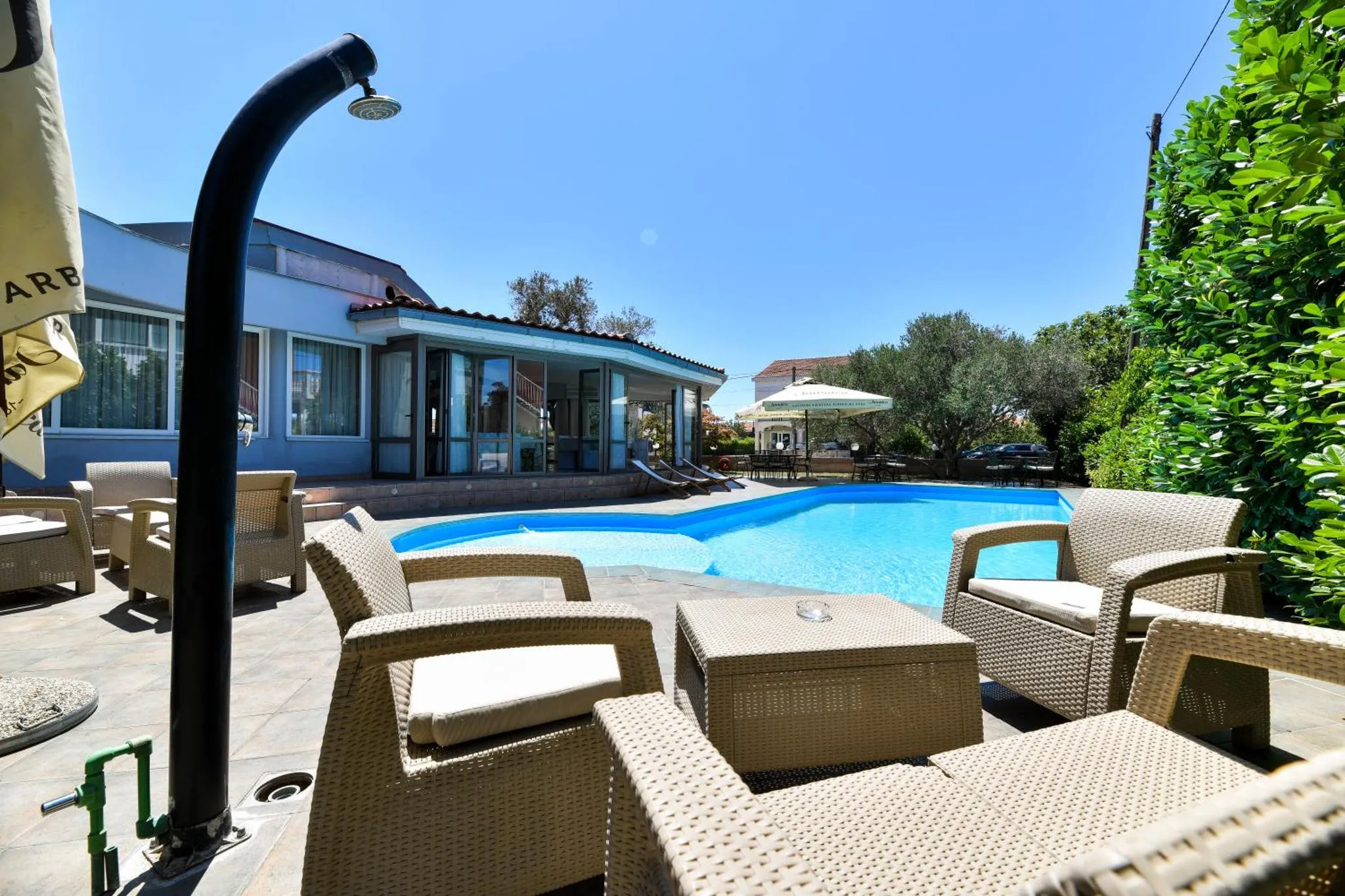 Terrasse avec mobilier en résine tressée donnant sur une piscine ensoleillée.