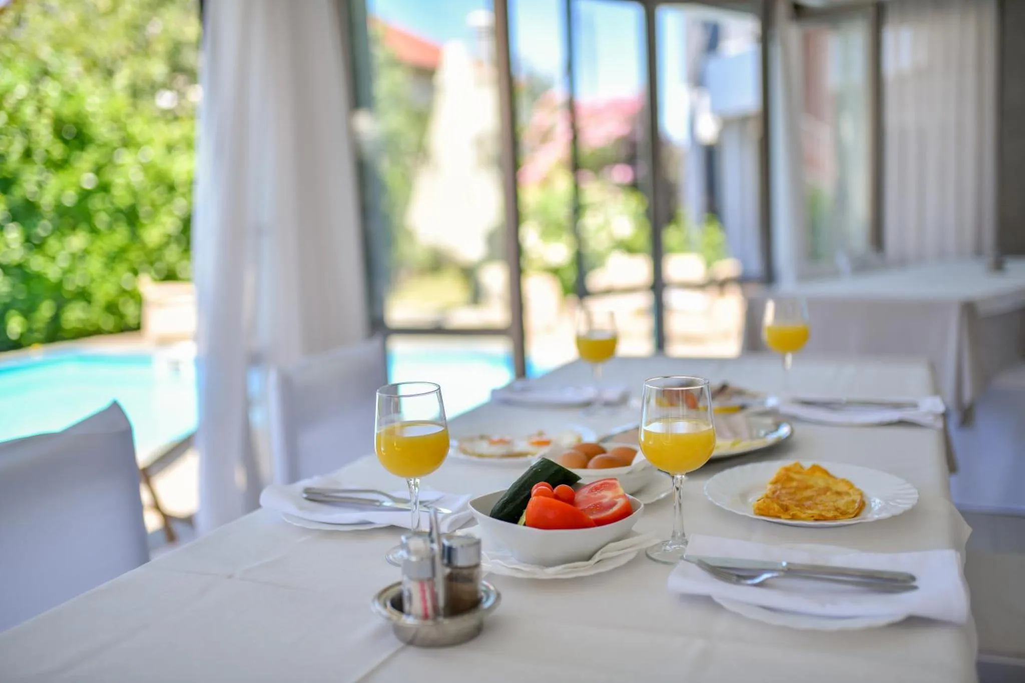 Une table est dressée avec des couverts, des assiettes et des verres de jus d'orange.