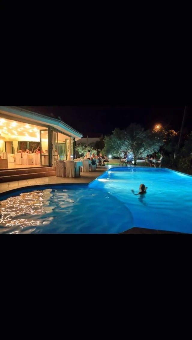 Une piscine illuminée avec des personnes se relaxant sur des transats et dans l'eau.