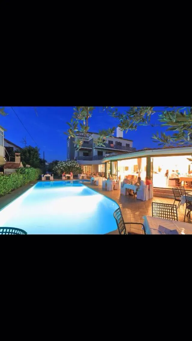 Une piscine illuminée au crépuscule avec des transats et une végétation luxuriante.