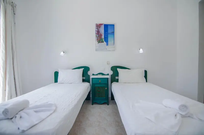Une chambre lumineuse avec deux lits simples et une décoration murale.