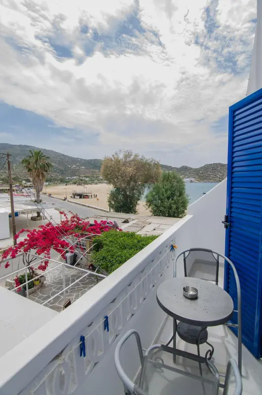 Vue d'un balcon fleuri sur une plage et des montagnes.