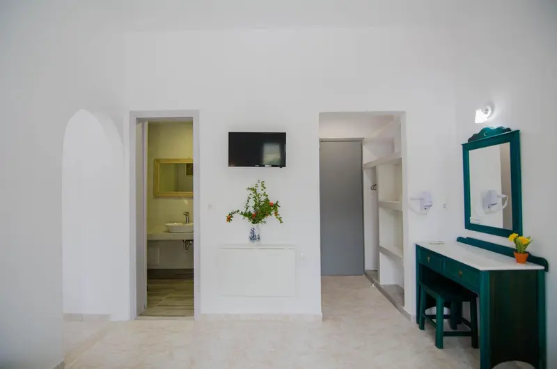 Une chambre lumineuse avec un téléviseur mural et une coiffeuse.