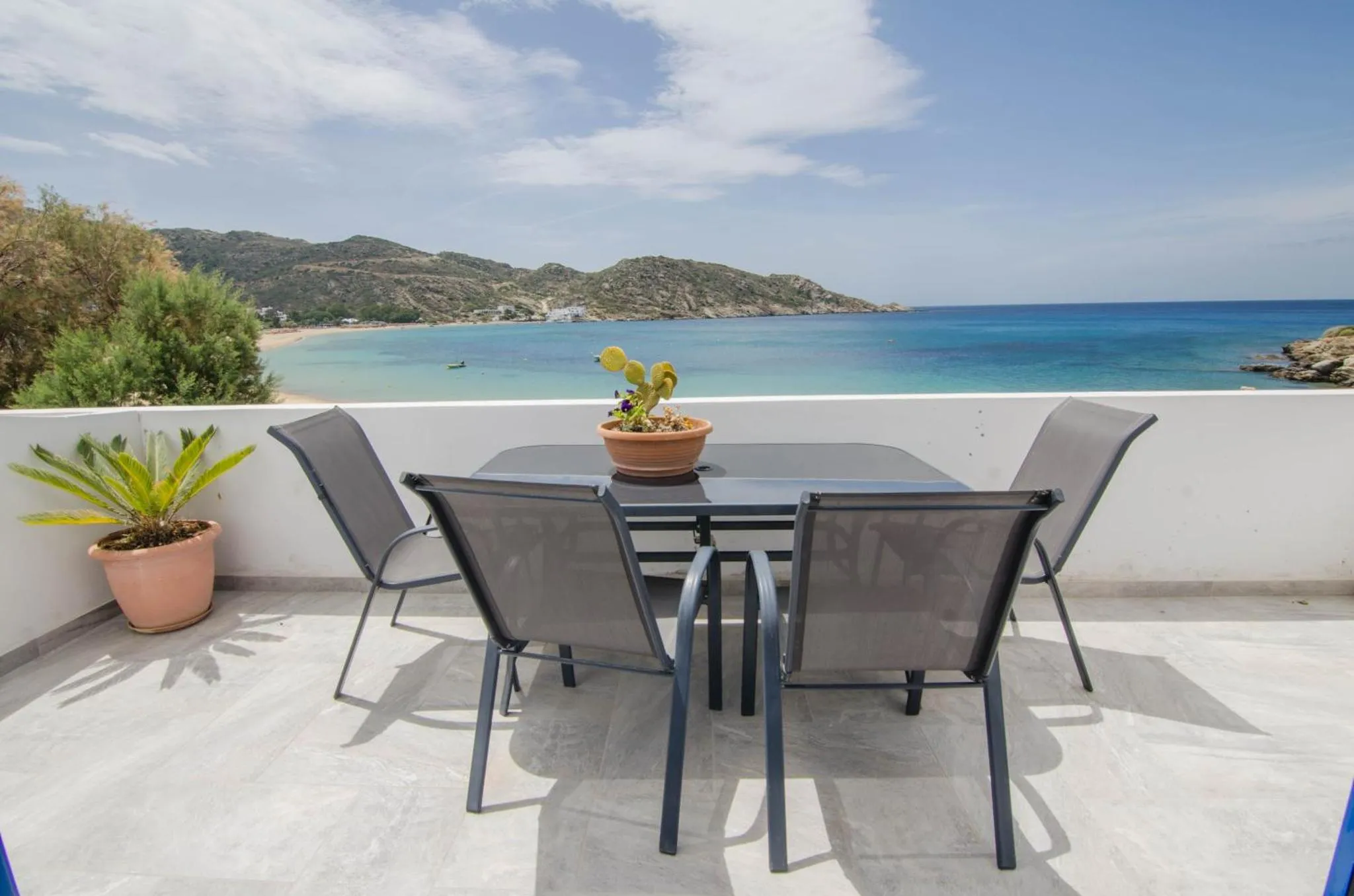 Une table et des chaises sont disposées sur une terrasse avec vue sur la mer et la côte.