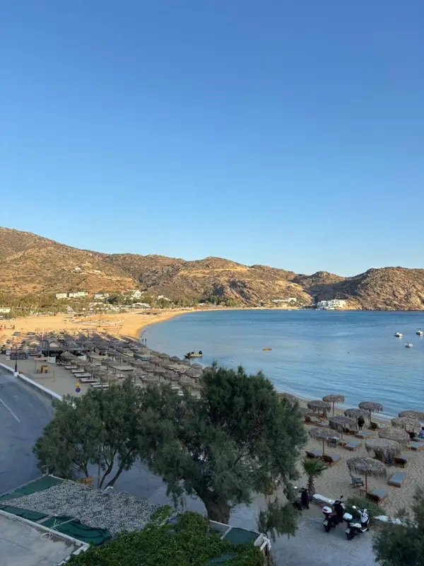 Vue aérienne d'une plage de sable fin bordée de parasols et d'une mer turquoise.
