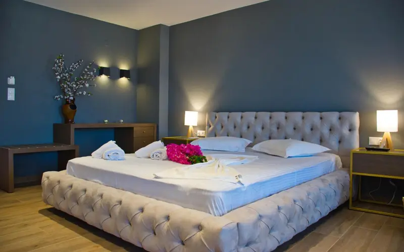 Une chambre avec un grand lit recouvert de draps blancs et de fleurs.