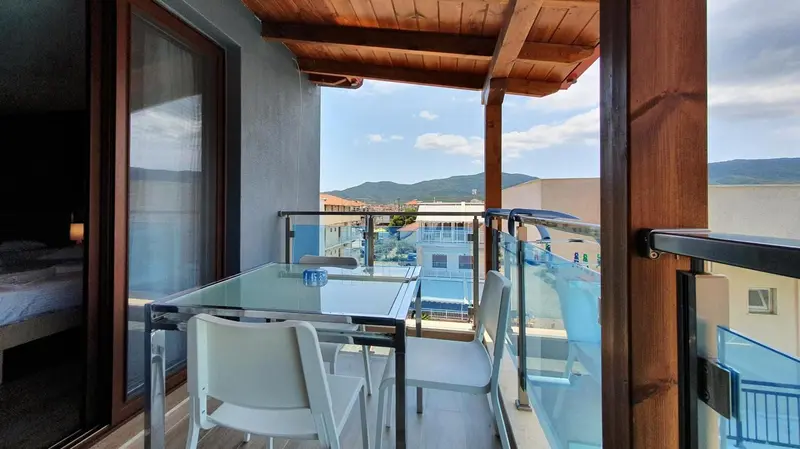 Une terrasse avec une table et des chaises offre une vue sur la ville et les montagnes.