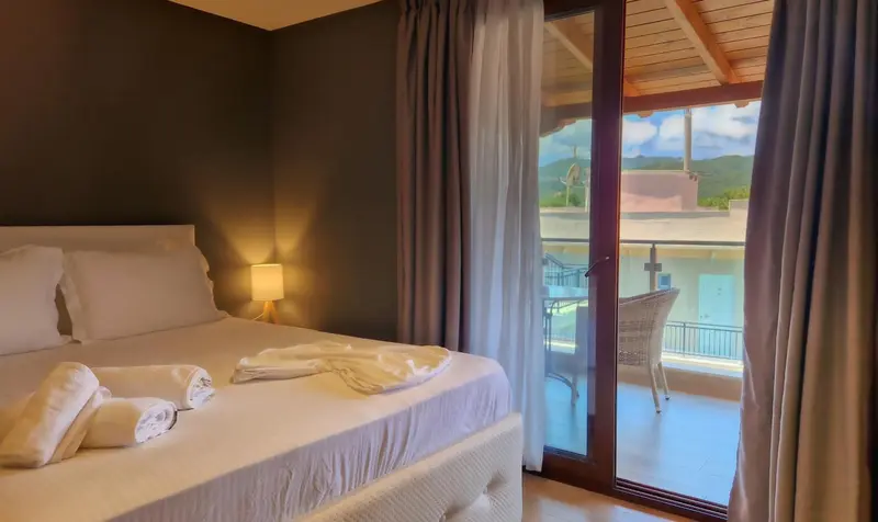 Une chambre lumineuse s'ouvre sur une terrasse avec vue sur un paysage montagneux.