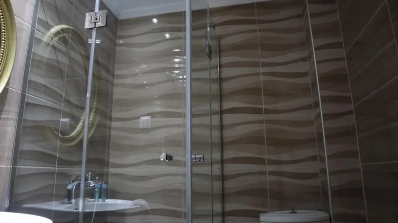 Une douche à l'italienne avec des carreaux marron ondulés.