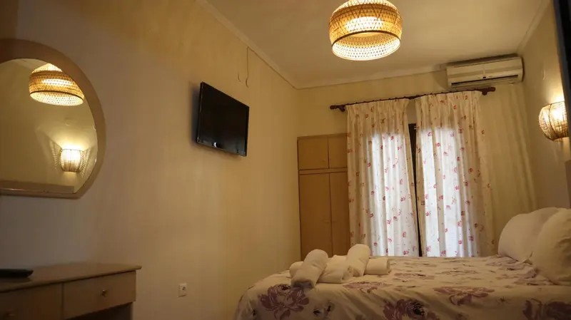 Une chambre lumineuse avec un lit recouvert d'une courtepointe florale et un miroir.